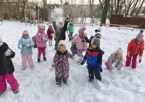 Na zdjęciu widzimy grupkę dzieci, które rzucają do góry śnieżkami.
