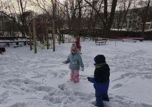 Na zdjęciu widzimy dzieci, które bawią się na śniegu.