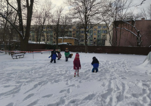 Na zdjęciu widzimy grupkę dzieci, które bawią się na śniegu.
