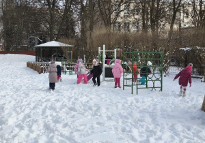 Na zdjęciu widzimy grupkę dzieci, które bawią się na śniegu.