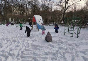 Na zdjęciu widzimy grupkę dzieci, które bawią się na śniegu.