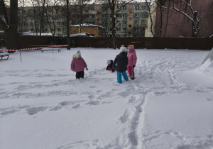Na zdjęciu widzimy grupkę dzieci, które bawią się na śniegu.