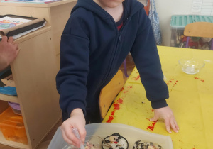 chłopiec, który za pomocą pipety uzupełnia wieczko wodą