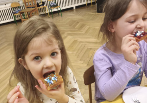 Dzieci jedzą śniadanie przy wspólnym stole w piżamach