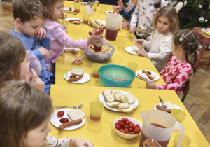 Dzieci jedzą śniadanie przy wspólnym stole w piżamach
