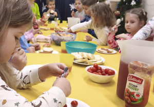 Dzieci jedzą śniadanie przy wspólnym stole w piżamach