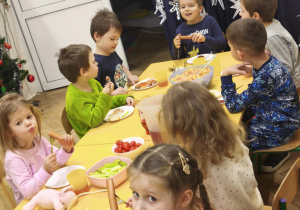 Dzieci jedzą śniadanie przy wspólnym stole w piżamach