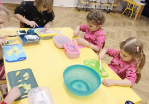 Dzieci jedzą śniadanie przy wspólnym stole w piżamach