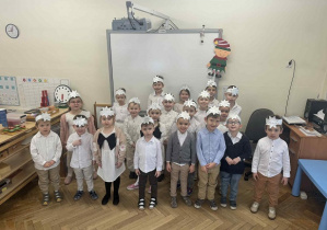 Zdjęcie przedstawia dzieci przed tablicą interaktywną, stojące w grupie, z opaskami z gwiazdką na głowie.