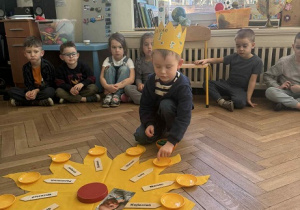 Zdjęcie przedstawia chłopca rozkładającego koraliki na słoneczku urodzinowym.