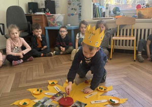 Zdjęcie przedstawia chłopca wkładającego świeczkę w drewniany tort.