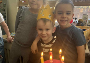 Zdjęcie przedstawia chłopca otoczonego kolegami, przy torcie ze świeczkami.