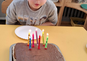 chłopiec zdmuchuje świeczki na torcie