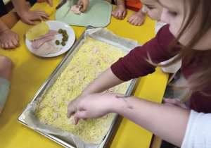 Dzieci przygotowują wspólnie pizzę