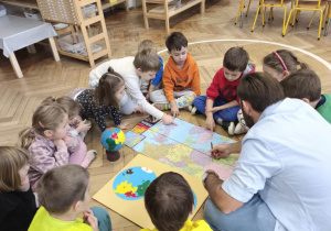 Dzieci siedząc w kręgu rozmawiają z gościem, tatą Aleksa.