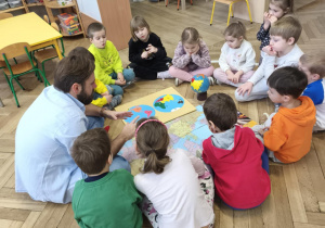 Dzieci siedząc w kręgu rozmawiają z gościem, tatą Aleksa.