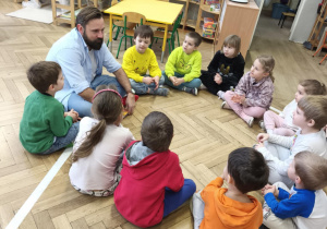 Dzieci siedząc w kręgu rozmawiają z gościem, tatą Aleksa.