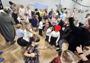 Na zdjęciu widzimy dziadków bawiących się ze swoimi wnukami w zabawy ruchowe.