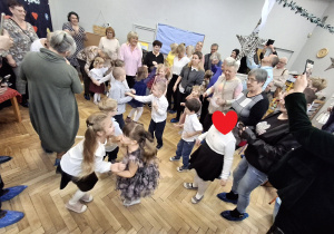 Na zdjęciu widzimy dziadków bawiących się ze swoimi wnukami w zabawy ruchowe.