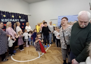 Na zdjęciu widzimy dziadków bawiących się ze swoimi wnukami w zabawy ruchowe.