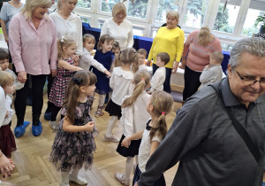 Na zdjęciu widzimy dziadków bawiących się ze swoimi wnukami w zabawy ruchowe.