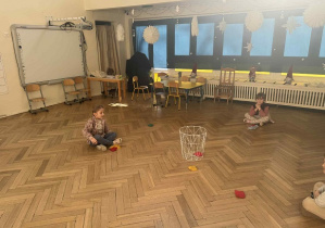 Zdjęcie przedstawia dzieci siedzące wokół kosza.