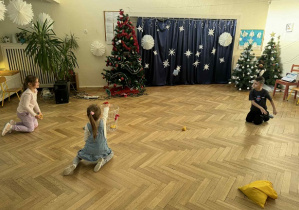 Zdjęcie przedstawia dziewczynkę rzucającą woreczkiem do kosza.