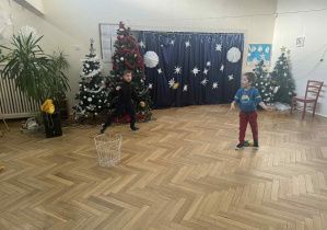 Zdjęcie przedstawia chłopca rzucającego woreczkiem do kosza.