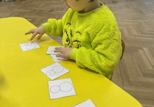 Zdjęcie przedstawia chłopca układającego obrazki według odpowiedniej kolejności.