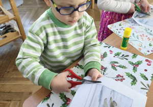 Na zdjęciu widzimy chlopca, który wycina puzzle z niedźwiedziem polarnym.