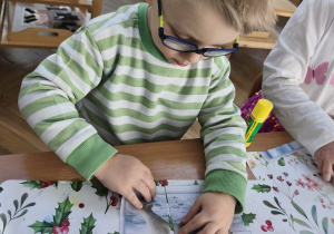 Na zdjęciu widzimy chłopca, który przykleja wycięte puzzle z niedźwiedziem polarnym.