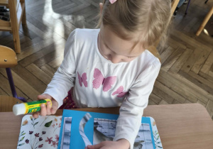 Na zdjęciu widzimy dziewczynkę, która przykleja wycięte puzzle z niedźwiedziem polarnym.