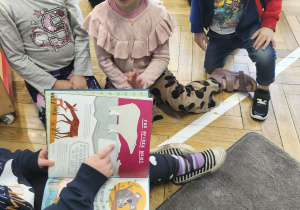 Na zdjęciu widzimy dzieci, które poszukują w książkach wiadomości i ilustracji o niedźwiedziu polarnym.
