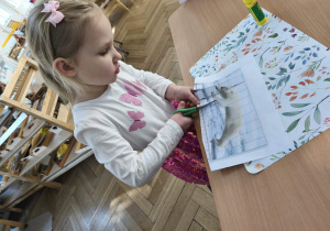 Na zdjęciu widzimy dziewczynkę, która wycina puzzle z niedźwiedziem polarnym.