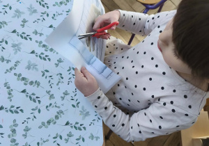 Na zdjęciu widzimy dziewczynkę, która wycina puzzle z niedźwiedziem polarnym.