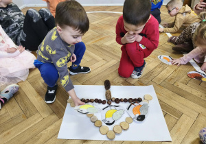 Na zdjęciu widzimy dwóch chłopców, którzy położyli swoje ptaszki na karmniku.