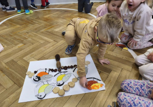 Na zdjęciu widzimy chłopca, który kładzie wykonanego ptaszka na karmniku z materiału przyrodniczego.
