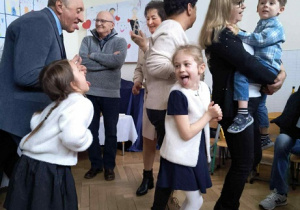 Zdjęcie przedstawia dziadków z dziećmi z wytkniętymi językami podczas zabawy integracyjnej.