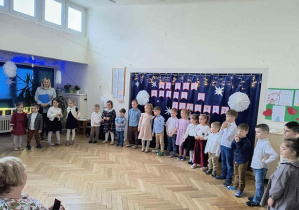 Zdjęcie przedstawia dzieci stojące w półkolu podczas występu.