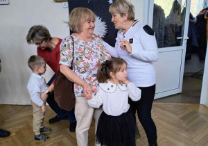 Zdjęcie przedstawia dwie kobiety rozmawiające ze sobą, Jedna trzyma dziewczynkę za rękę.