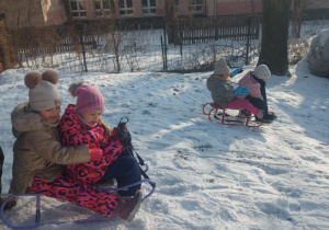 Dzieci zjeżdżające na sankach z górki
