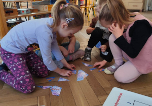 grupa dzieci układająca obrazek z pociętych puzzli