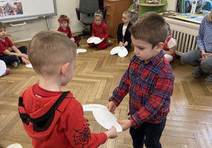 Zdjęcie przedstawia chłopca wręczającego chłopcu obrazek w kształcie serca.