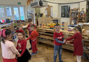 Zdjęcie przedstawia dzieci dobrane w pary, tworzące kółeczka podczas wspólnej zabawy.