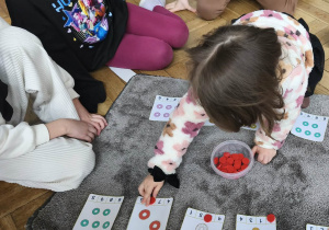 Na zdjęciu widzimy dziewczynkę, która przelicza donaty.