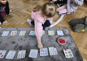 Na zdjęciu widzimy dziewczynkę, która przelicza donaty.