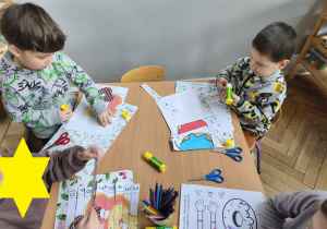 Na zdjęciu widzimy grupkę dzieci, które wykonują pracę plastyczną.