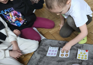 Na zdjęciu widzimy chłopca, który przelicza donaty.