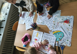 Na zdjęciu widzimy grupkę dzieci, które wykonują pracę plastyczną.