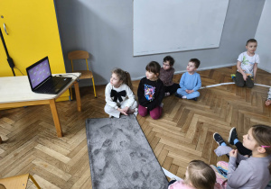 Na zdjęciu widzimy grupkę dzieci, które oglądają film o historii tłustego czwartku.